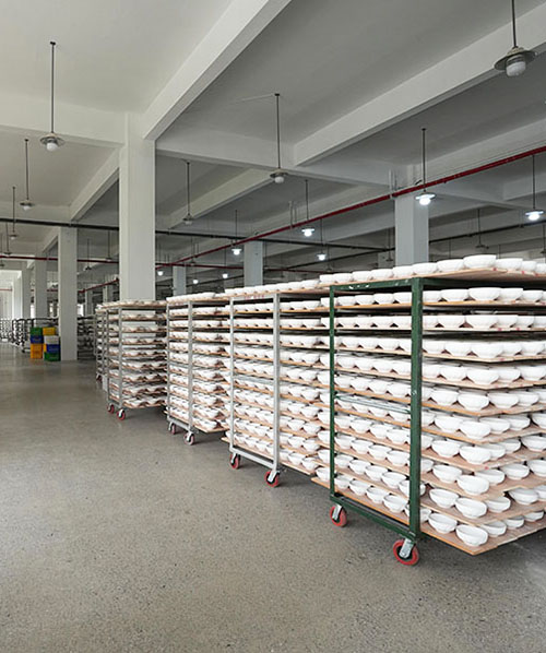 About 6 Massive inventory of wholesale ceramic bowls and mugs on rolling drying racks inside our Chaozhou factory supply chain.