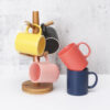 black-and-coral-stonwear-mugs Matte black and coral red stoneware coffee mugs displayed on a clean minimalist commercial backdrop.