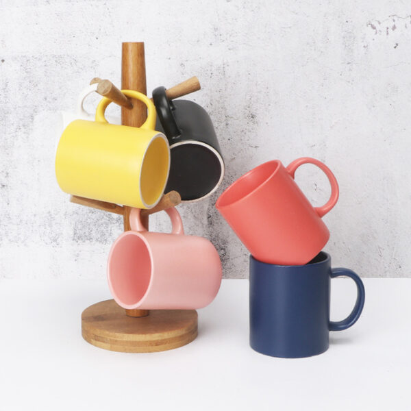 black-and-coral-stonwear-mugs Matte black and coral red stoneware coffee mugs displayed on a clean minimalist commercial backdrop.