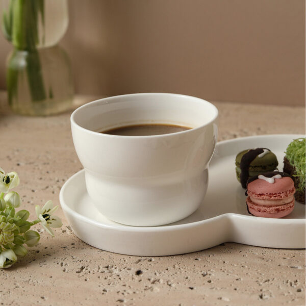 minimalist-bistro-tableware-wholesale Minimalist bistro tableware display featuring glossy white ceramic cup and saucer sets on a stone countertop.