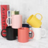 minimalist-solid-color-coffee-cups Navy blue and cream white matte ceramic coffee cups stacked neatly next to decorative studio books.