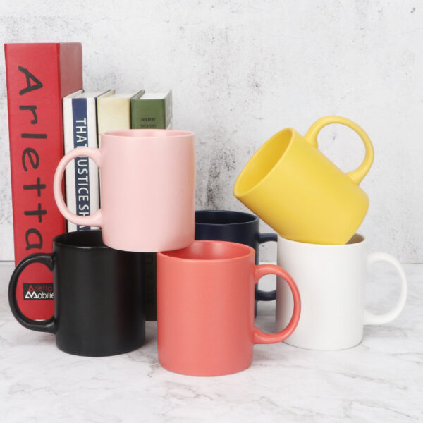 minimalist-solid-color-coffee-cups Navy blue and cream white matte ceramic coffee cups stacked neatly next to decorative studio books.