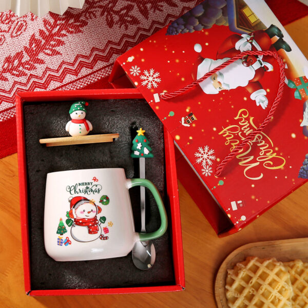 snowman-ceramic-coffee-cup A white snowman ceramic coffee cup with a green handle next to a matching snowman spoon and green lid base.