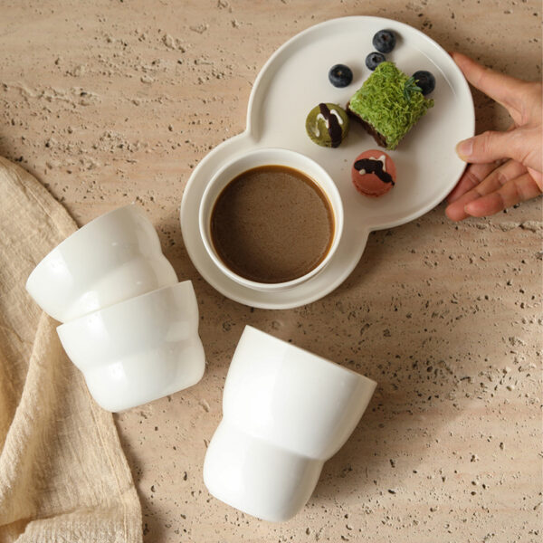stackable-handless-ceramic-cups A stack of white glossy handless ceramic cups with a distinctive wavy textured design for space-saving storage.
