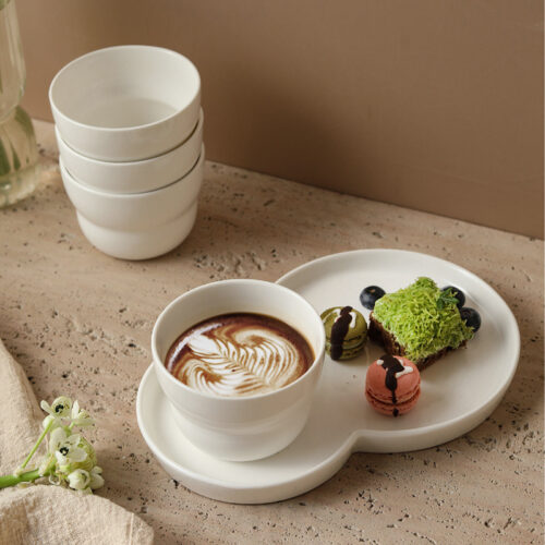 wholesale-ceramic-cup-and-saucer-set Wholesale minimalist ceramic cup and saucer set with a 2-in-1 dessert plate serving coffee and pastries.