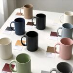 custom color matching ceramic mugs displayed with Pantone color swatch cards on a clean white studio table for private label buyers