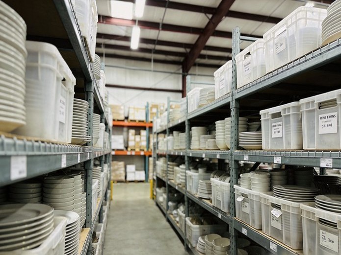 organized ceramic plate inventory in reusable storage crates inside an event rental warehouse