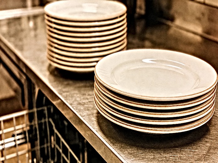 durable ceramic dinner plates stacked on commercial kitchen counter for university dining comparison