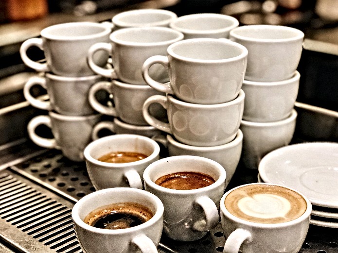 stacked white ceramic coffee cups and mugs in a commercial restaurant setting for high-volume brunch service