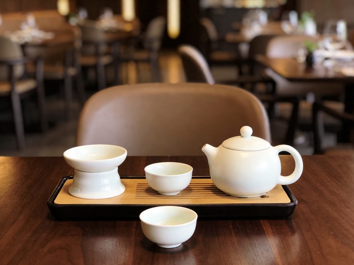 ceramic tea sets for restaurants displayed on dark walnut table with teapot and tasting cups