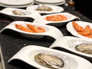 seafood restaurant ceramic tableware with oyster plates and shrimp dishes displayed on a dark granite countertop