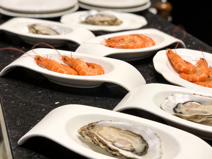 seafood restaurant ceramic tableware with oyster plates and shrimp dishes displayed on a dark granite countertop