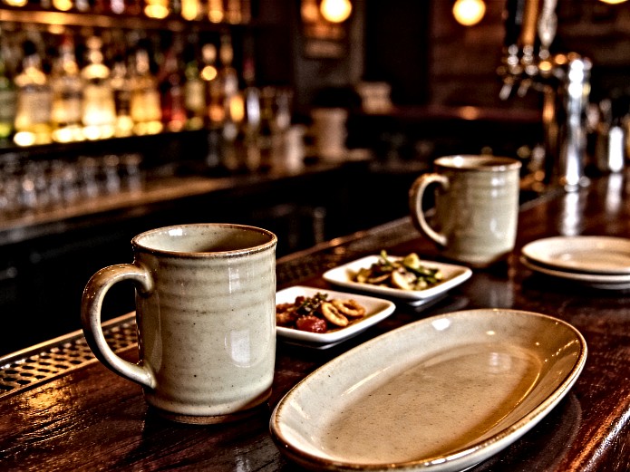 Ceramic Tableware for Bars: B2B Sourcing Guide 2 ceramic tableware for bars including mugs, plates, and shareable platters arranged on a commercial bar counter