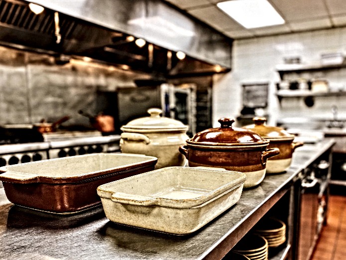 ceramic baking dishes and casserole pots arranged on stainless steel commercial kitchen counter for restaurant sourcing