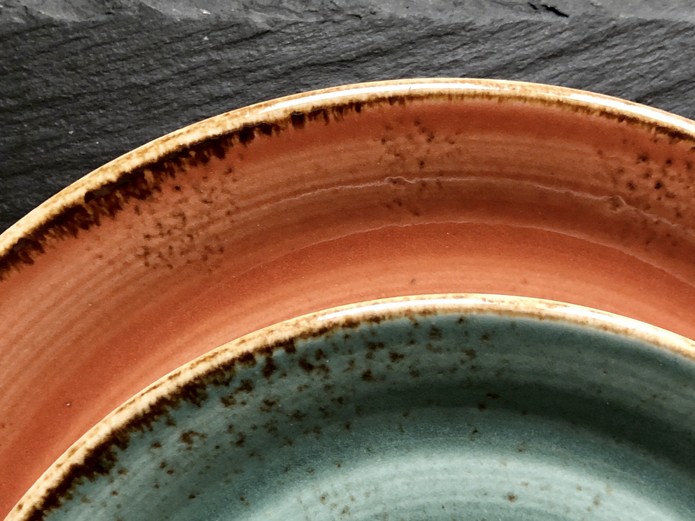 reactive earth-tone ceramic glazes in terracotta and sage colors showing organic hand-finished rim textures for rustic tableware