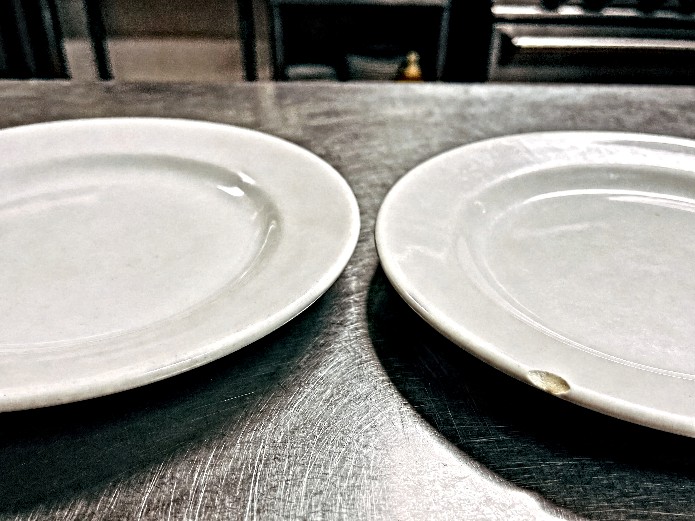 Ceramic Tableware Reorder Strategy: How Restaurants and Hotels Calculate Optimal Restock Cycles 2 ceramic plate chip inspection on stainless steel counter demonstrating replacement need for restaurant dinnerware