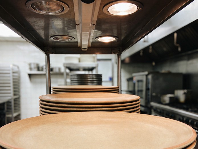 heat resistant ceramic plates stacked on stainless steel shelving in a commercial restaurant kitchen