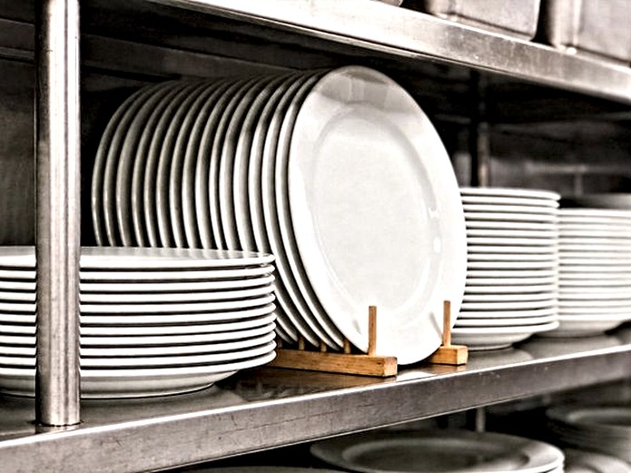 stacked white ceramic plates on stainless steel shelf in professional restaurant storage