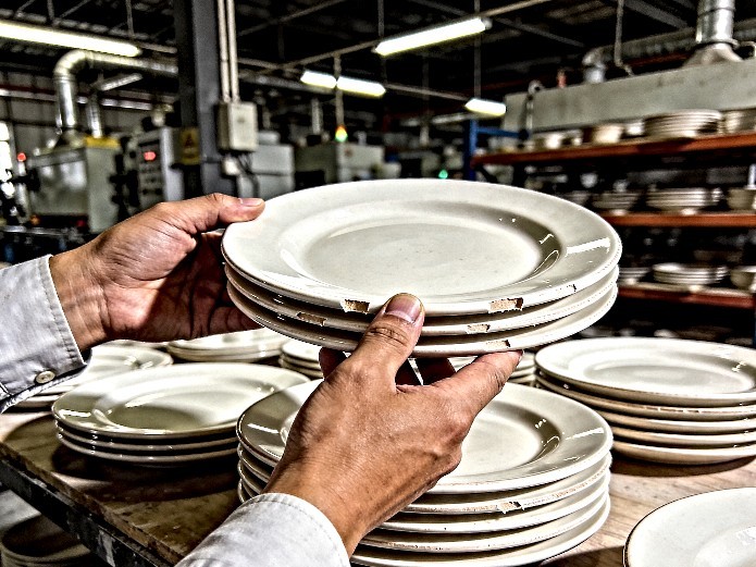 quality control inspector examining ceramic plates for Mexican restaurant tableware in a factory setting