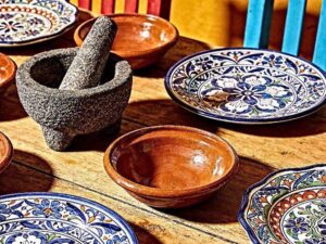 ceramic tableware for Mexican restaurants displayed with traditional Talavera plates, terracotta bowls, and molcajete on a wooden table