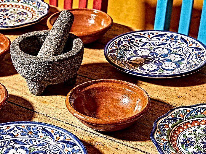 ceramic tableware for Mexican restaurants displayed with traditional Talavera plates, terracotta bowls, and molcajete on a wooden table