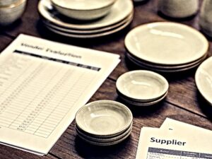 ceramic tableware vendor scorecard spreadsheet on wooden desk with dinnerware samples for B2B buyers