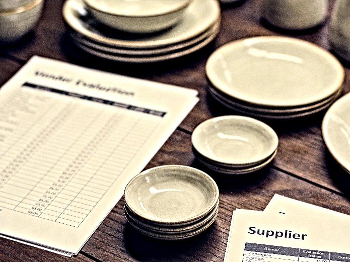 ceramic tableware vendor scorecard spreadsheet on wooden desk with dinnerware samples for B2B buyers