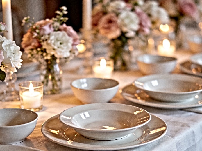 ceramic tableware for wedding rentals displayed on elegant reception table with floral centerpieces and candlelight