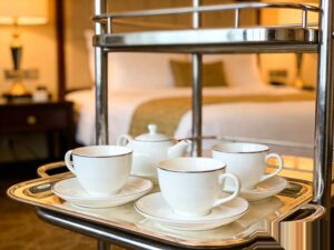 hotel room service ceramic tableware displayed on polished silver room service trolley in luxury hotel setting