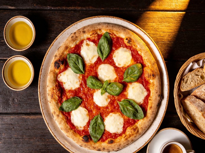 Neapolitan pizza on large ceramic plate with olive oil dishes for Italian restaurant service