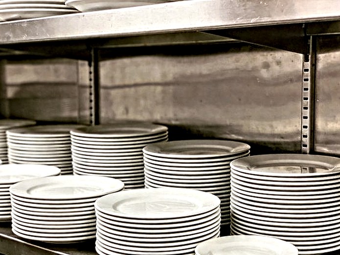 stacked ceramic dinnerware for culinary training programs organized on stainless steel storage racks