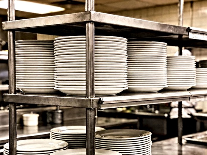 stackable ceramic tableware neatly stacked on stainless steel kitchen shelving for restaurant storage efficiency